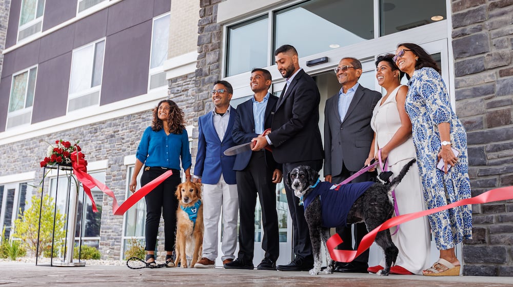 Joshua and Roshan Patel (center) cut a ribbon surrounded by family members to celebrate the opening of a dual-branded Mariott near the Mall at Fairfield Commons, Sept. 5, 2025. The family owns and operates Scarlet and Gray Hospitality.  BRYANT BILLING / STAFF