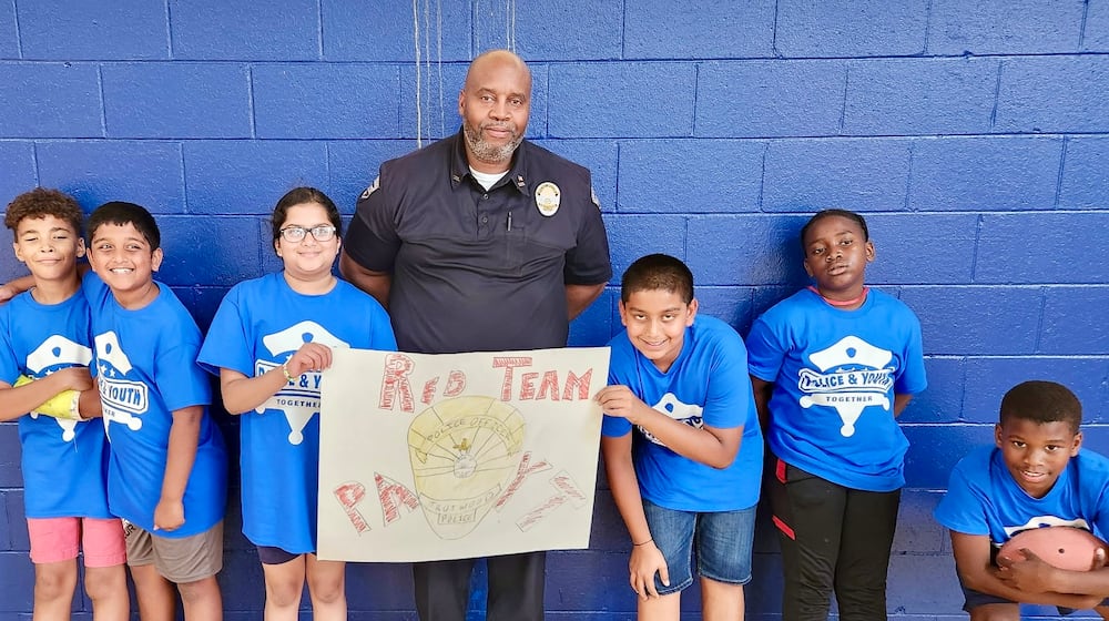 Trotwood Police Officer Tyrone Derrick with students from one of his police explorer program classes. CONTRIBUTED