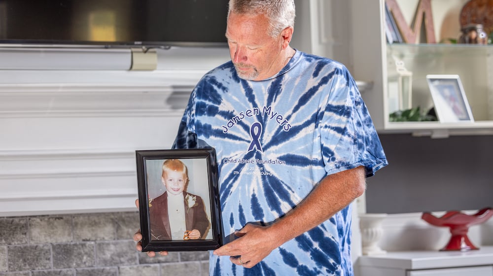 Bryan Myers, who has been selected as a Dayton Daily News Community Gem, looks at a photo of his son Jansen, who died in 2001. He launched the Jansen Myers Child Abuse Foundation in his son's honor.  BRYANT BILLING / STAFF