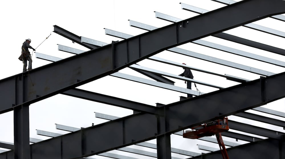Construction workers guide a roof beam into place as work continues on the second phase of the Topre plant. Bill Lackey/Staff