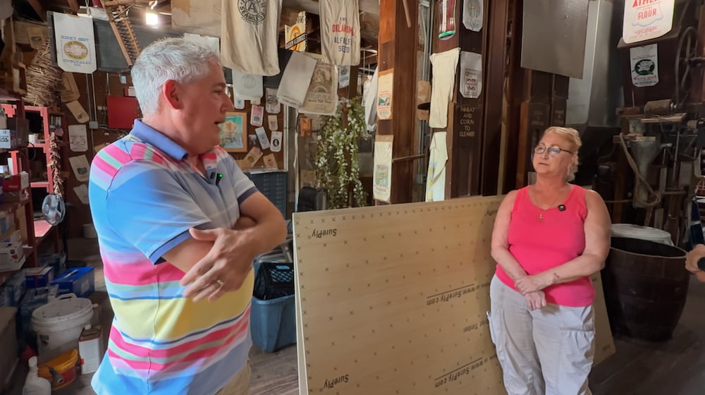 Councilmembers Anthony Satariano and Paula Lazorski stand inside the Historic Clifton Mill, surrounded by flour sack displays and mill equipment.