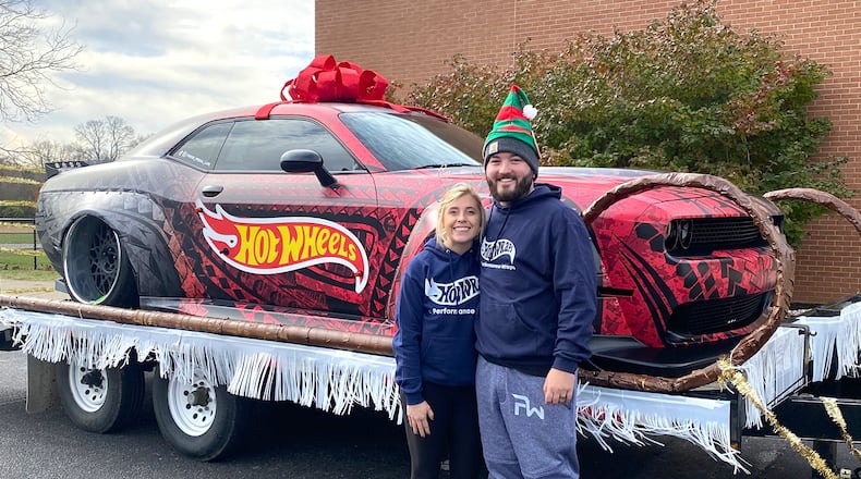 Andrew Banks (R) and his wife, Tanor, in front of a car their company, Performance Wraps, customized with a vinyl wrap.