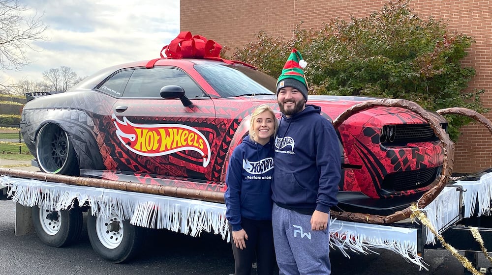 Andrew Banks (R) and his wife, Tanor, in front of a car their company, Performance Wraps, customized with a vinyl wrap.