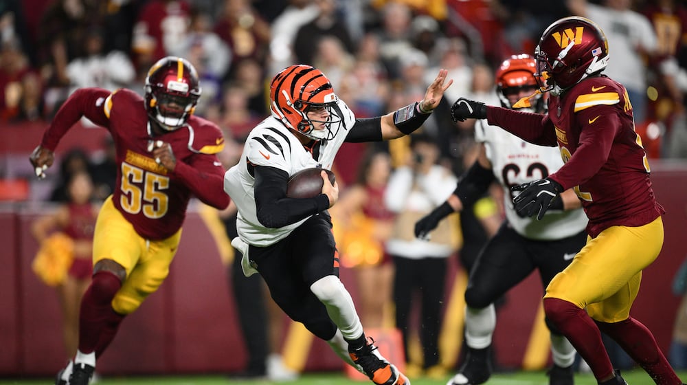 Cincinnati Bengals quarterback Joe Burrow, center, scrambles as Washington Commanders defensive end Jacob Martin (55) and defensive end Dorance Armstrong, right, defend during the first half of a preseason NFL football game Monday, Aug. 18, 2025, in Landover, Md. (AP Photo/Nick Wass)