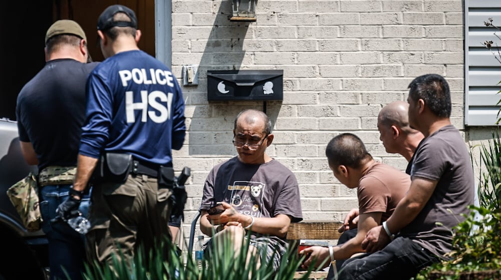 Homeland Security officers and local law enforcement agencies raided a home in the 1100 block of Irving Ave. in Dayton on Friday, July 26. While authorities went in and out of the house, seven people sat outside in zip-tie cuffs. JIM NOELKER / STAFF