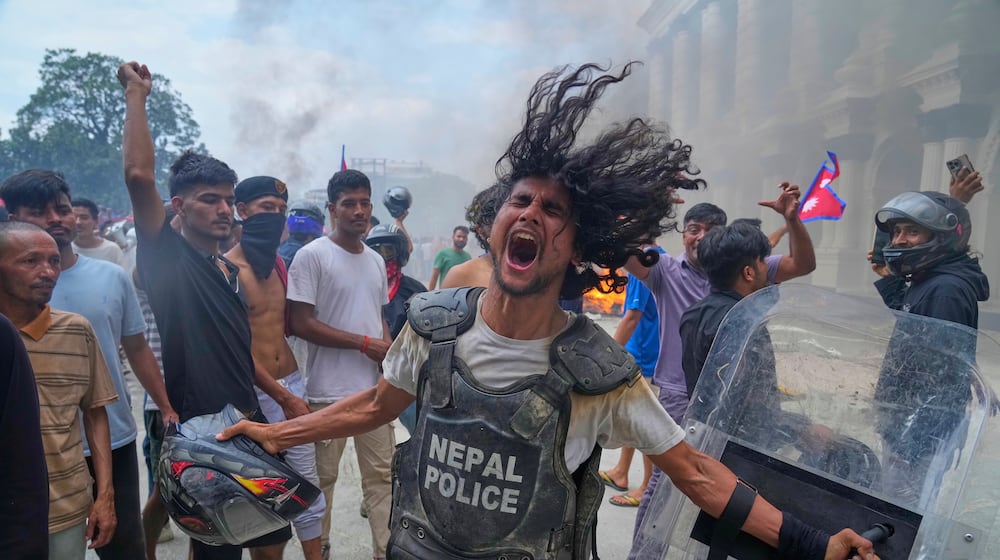 A protester wearing flak jacket and carrying a shield snatched from a policeman shouts slogans at the Singha Durbar, the seat of Nepal's government's various ministries and offices during a protest against social media ban and corruption in Kathmandu, Nepal, Tuesday, Sept. 9, 2025. (AP Photo/Niranjan Shrestha)