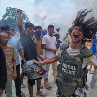 A protester wearing flak jacket and carrying a shield snatched from a policeman shouts slogans at the Singha Durbar, the seat of Nepal's government's various ministries and offices during a protest against social media ban and corruption in Kathmandu, Nepal, Tuesday, Sept. 9, 2025. (AP Photo/Niranjan Shrestha)