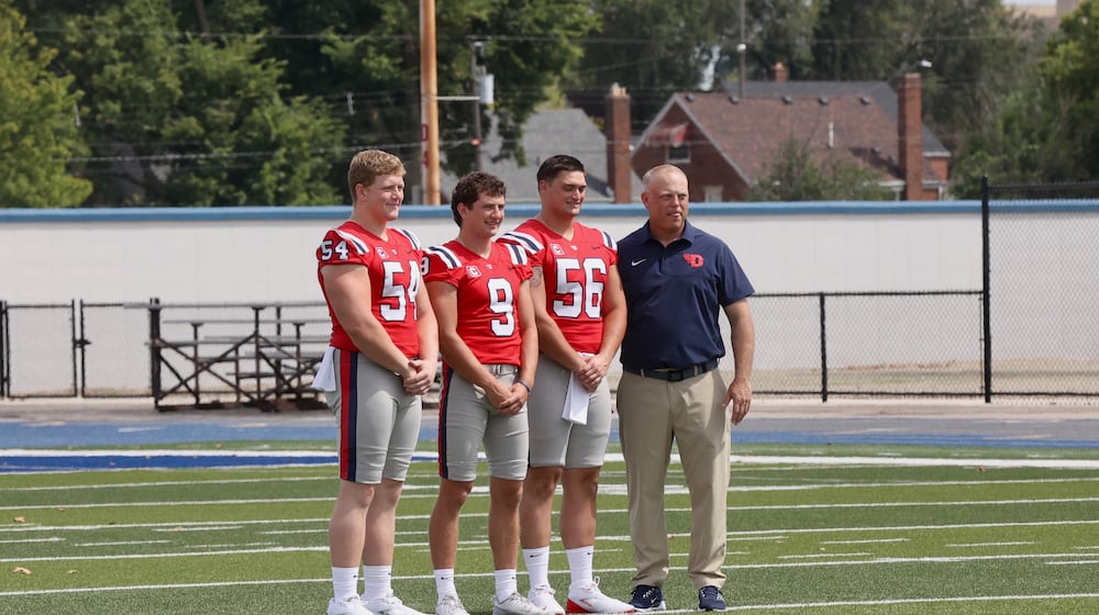 Dayton football coach Trevor Andrews, right, poses for a photo with team captains Ben Huefner (54), Cam Cope (9) and Ryan Iiams at Media Day on Sunday, Aug. 17, 2025, at Welcome Stadium. David Jablonski/Staff