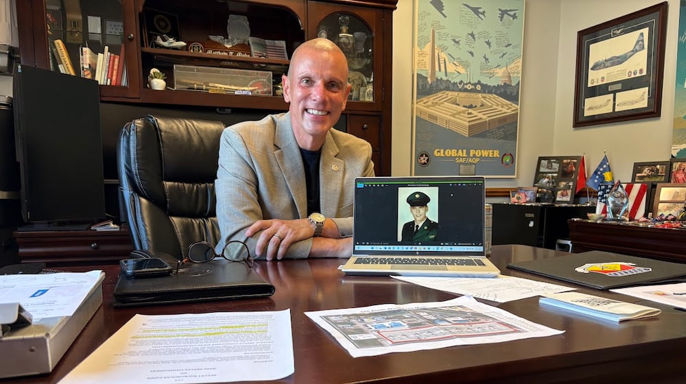 Col. Matthew Muha, deputy commander of the 445th Airlift Wing at Wright-Patterson Air Force Base, with a U.S. Army basic training photograph of his father, Thomas, who served during the Vietnam War. Muha is also director of the Autonomy Capability (ACT3) Team, at the Air Force Research Laboratory, also at Wright-Patterson. THOMAS GNAU/STAFF
