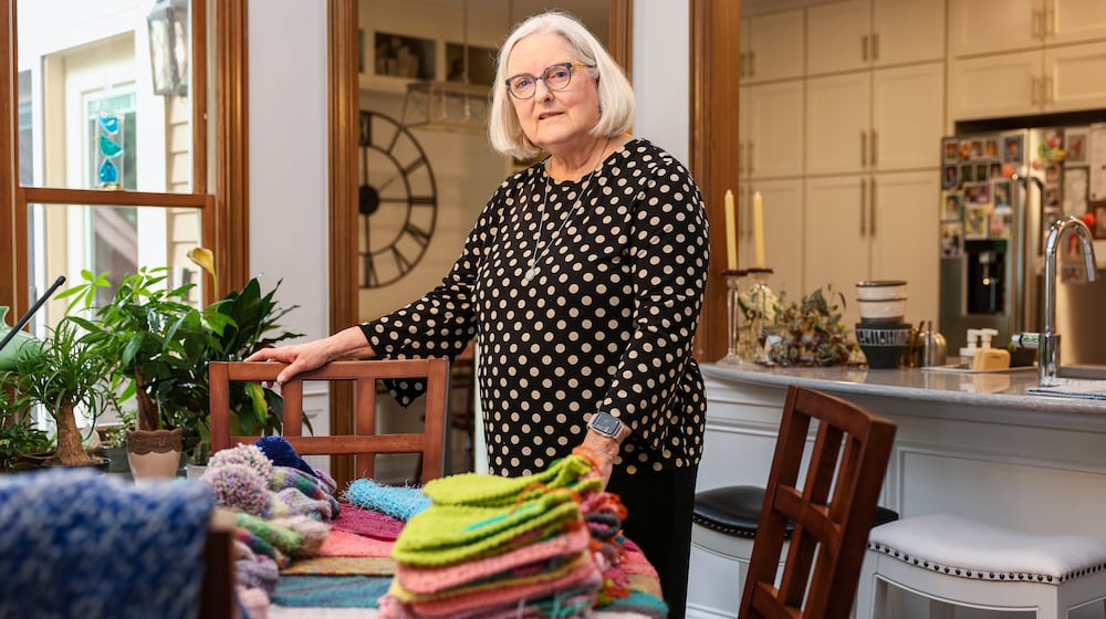 Mary Gaier has been named a Dayton Daily News Community Gem for donating items she has knitted to area charities. She stands behind her knitted wash cloths, shawls and hats on July 21, 2025. BRYANT BILLING / STAFF