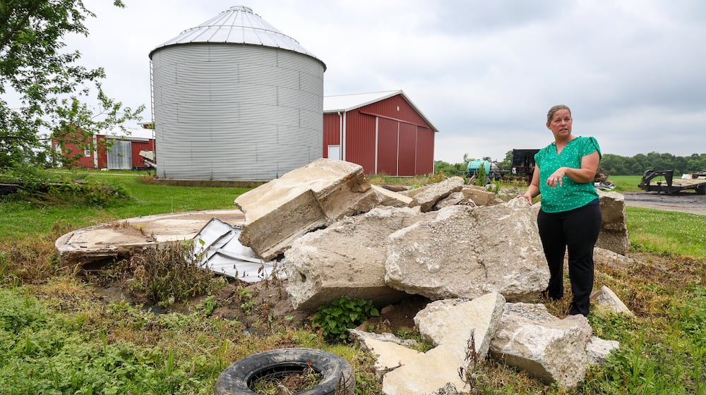Jennifer Vollmer talks about tornado damage her property sustained while standing in front of the remains of a grain bin that was destroyed during the storm last year. BRYANT BILLING / STAFF